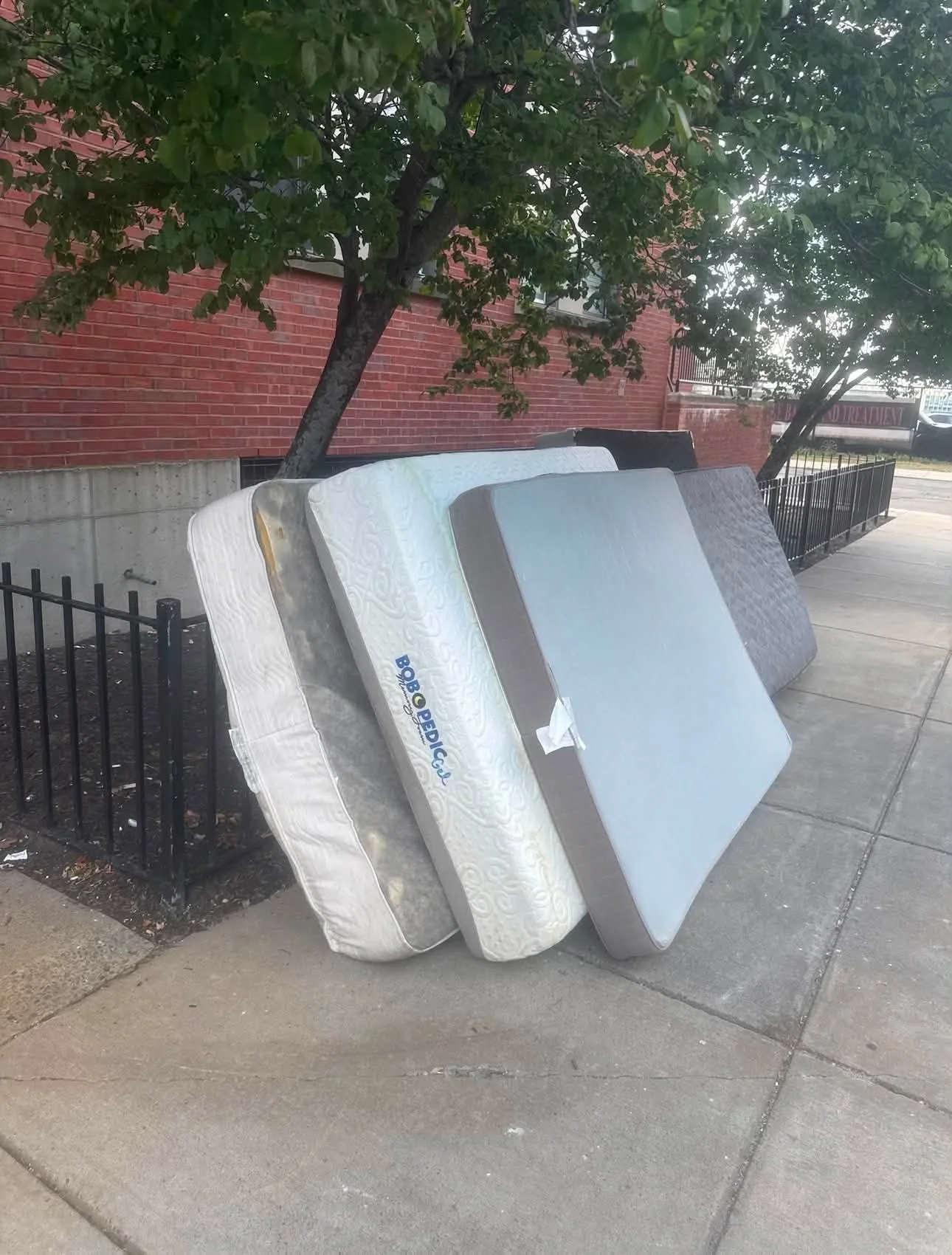 Stacked mattresses and box springs placed curbside for professional junk removal in Spokane